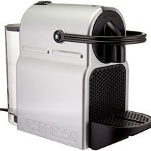 Silver Nespresso Inissia Espresso Machine with a compact design, featuring a folding drip tray and programmable coffee options. 